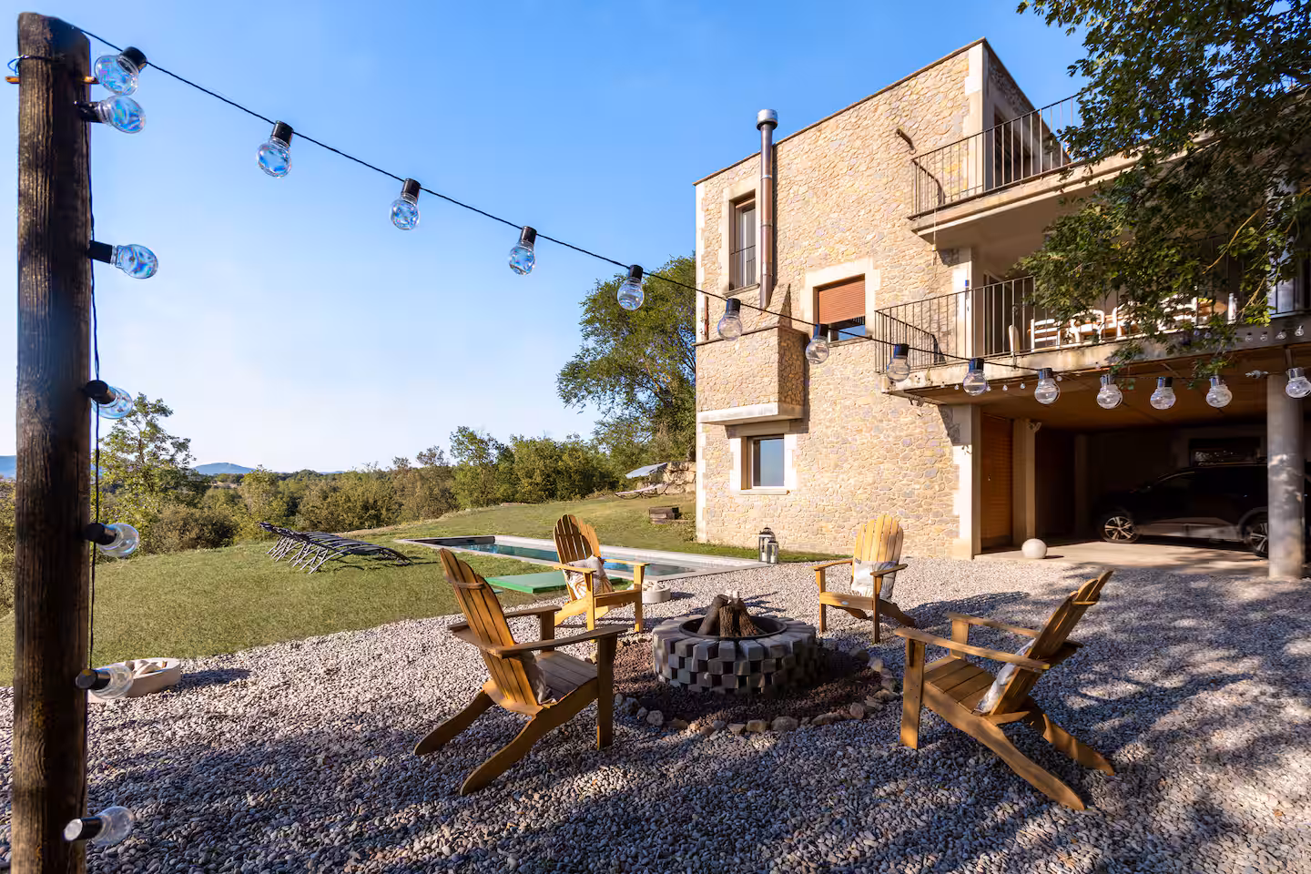 Terrasse extérieure avec feu de camp et guirlandes lumineuses